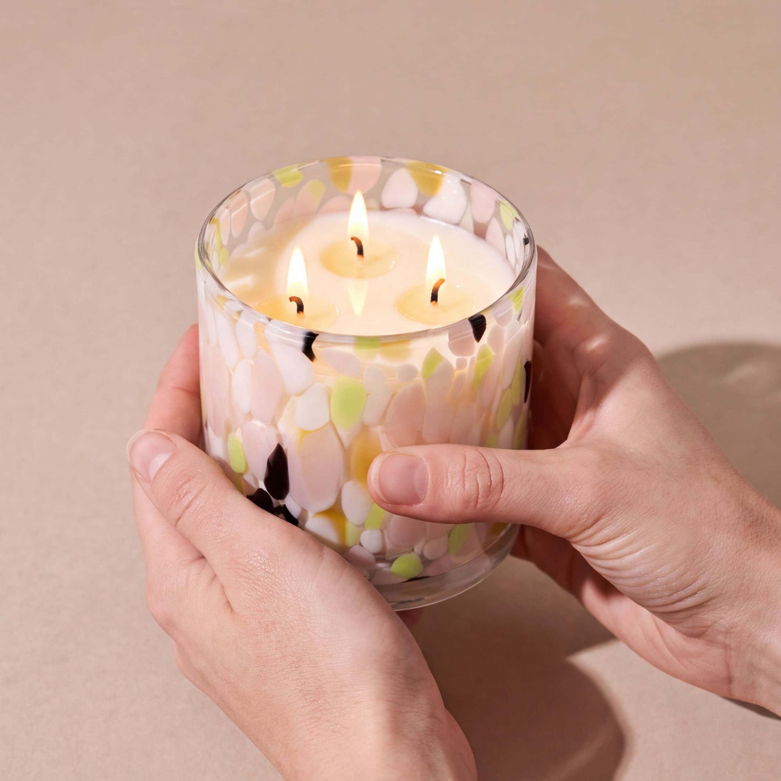 The Deodoriser Candle, lit and held in two hands to show its size